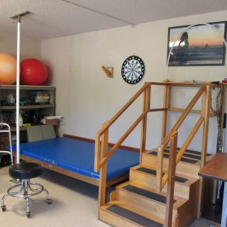 A physical therapy room equipped with exercise equipment and stairs for rehabilitation exercises.