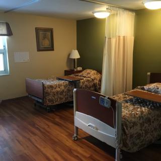 A hospital room with two beds separated by a curtain.