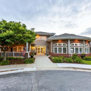 A large, luxurious house with well-maintained landscaping and a prominent driveway.
