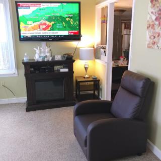A cozy living room with a television, recliner chair, fireplace, and a lamp.
