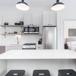 A sleek and modern kitchen featuring minimalist design with white decor and stainless steel appliances.
