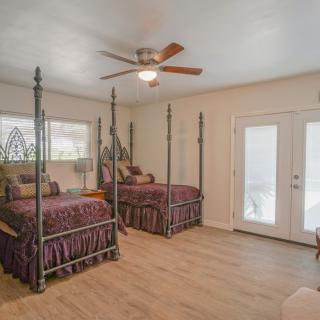 A cozy bedroom featuring twin beds with a ceiling fan and hardwood flooring.