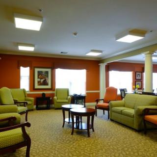 A cozy living room with sofas, chairs, and tables arranged on a carpeted floor.