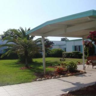 A well-maintained house with a garden and palm trees, featuring a covered porch and pathway.