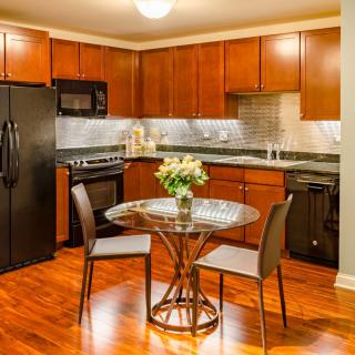 A modern kitchen with wooden cabinets, featuring a small dining area and essential appliances.