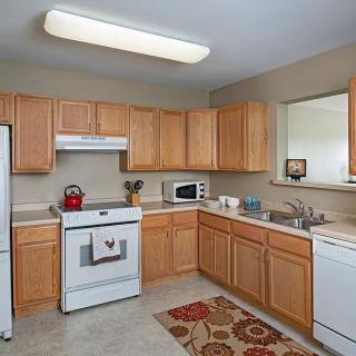 A modern kitchen with wooden cabinets and essential appliances.