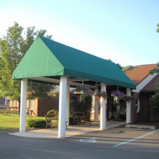 A building entrance with a green canopy supported by white columns.
