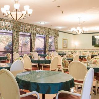 An elegant dining area with round tables, upholstered chairs, and decorative chandeliers.