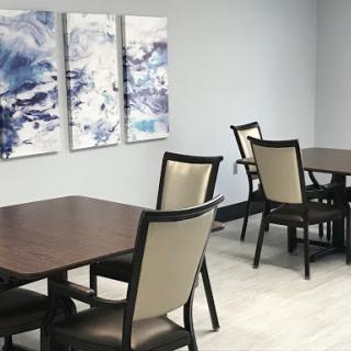 A modern dining area featuring wooden tables and upholstered chairs, complemented by abstract artwork on the walls.