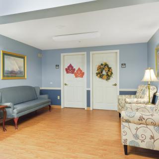 A cozy waiting area featuring a sofa, armchair, and decorated doors.