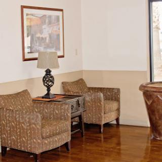 A cozy seating area featuring two wicker chairs, a decorative lamp, and artwork on the wall.