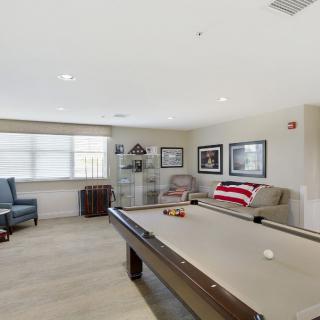 A well-lit game room featuring a pool table and comfortable seating.