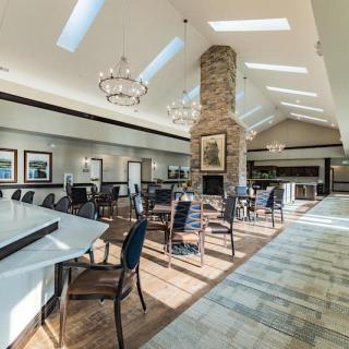A spacious, well-lit restaurant interior featuring a central fireplace and elegant chandeliers.