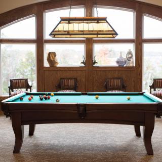 A cozy game room featuring a pool table with wooden furniture and decorative lighting.