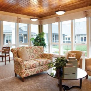 A cozy living room with elegant furniture and abundant natural light through large windows.