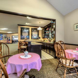 A cozy cafe interior with round tables covered in pink tablecloths and wooden chairs.