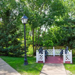 A picturesque garden scene featuring a small bridge and lamppost surrounded by lush greenery.