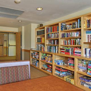 A cozy library space featuring wooden bookshelves filled with books and board games.