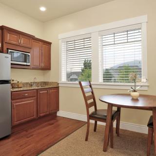 A cozy kitchen and dining area with wooden cabinets, a small round table, and two chairs by the window.