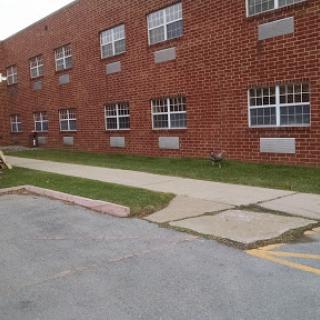 A brick building with multiple windows and a concrete sidewalk.