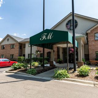 A building entrance with a green awning and surrounding landscaping.