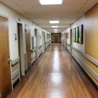 A view of a hospital hallway with rooms on either side.
