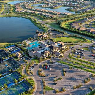 Aerial view of a suburban residential community with a lake and surrounding roads.