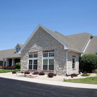 A single-story residential house with stone exterior and large windows in a suburban setting.