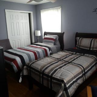 A cozy bedroom with two twin beds featuring striped bedding and a lamp by the window.