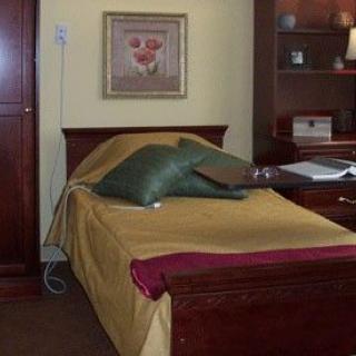 A cozy bedroom with a neatly made bed and wood furniture.