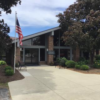 A modern government building featuring glass and brick architecture, with an American flag prominently displayed.