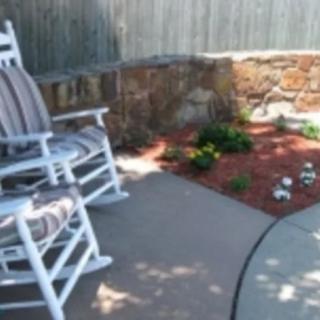 A cozy patio area featuring a rocking chair and a small garden.