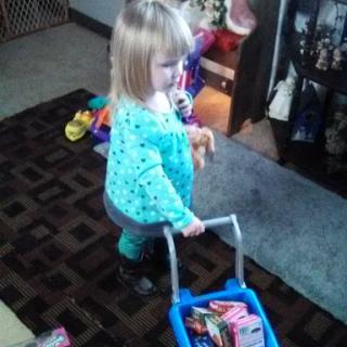 A toddler joyfully playing with a toy shopping basket filled with colorful items.