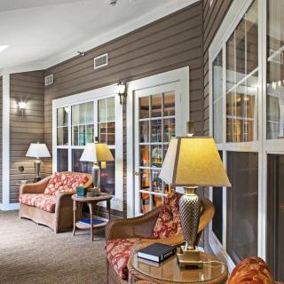 A cozy living area featuring comfortable seating, side tables with lamps, and large windows.