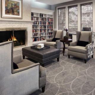 A cozy living room with a fireplace, armchairs, and bookshelves.
