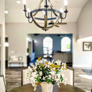 A beautifully styled dining room featuring a modern chandelier and a floral centerpiece.