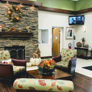A cozy waiting room with a stone fireplace, autumn-themed decorations, and comfortable seating.