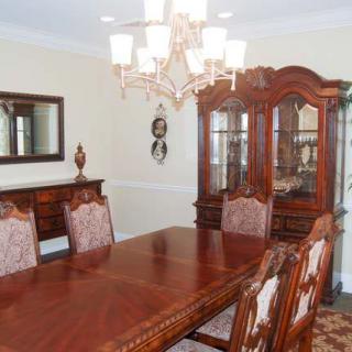 A traditional dining room with a large wooden table, ornate chairs, and a chandelier.