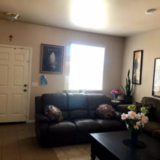 A cozy living room featuring a sofa, coffee table with flowers, and paintings on the wall.