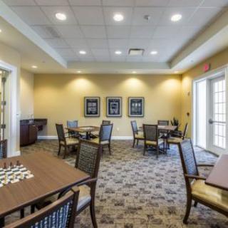 A well-lit meeting room with neatly arranged tables and chairs on a patterned carpet.