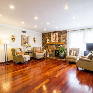 A spacious living room featuring a wooden floor, cozy seating area, and a stone fireplace adorned with decorative items.
