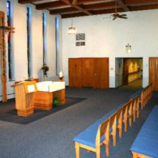 Interior view of a chapel with wooden pews and an altar.