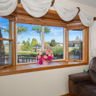 A cozy living room window adorned with elegant curtains, featuring a beautiful bouquet of flowers and a picturesque outdoor view.