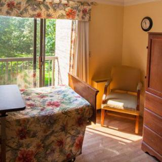 A cozy bedroom with a floral bedspread and natural sunlight streaming through the window.