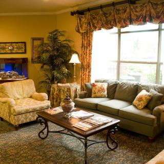 A cozy living room with a sofa, armchair, and coffee table near a large window.