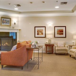 A cozy living room with comfortable sofas and armchairs arranged around a fireplace, accented by elegant decor and warm lighting.