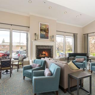 A cozy living room with comfortable seating, large windows, and a warm fireplace.