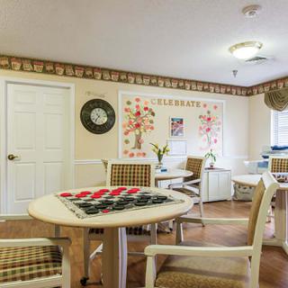 A cozy community game room featuring tables with checkers boards, comfortable chairs, and decorative elements.