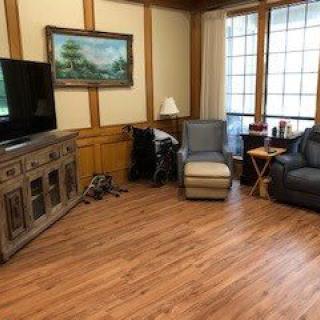 A cozy living room with a television, armchairs, and wooden flooring.