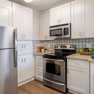 A modern kitchen featuring stainless steel appliances and white cabinets.